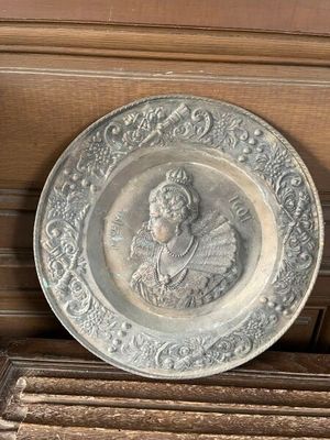 une assiette en argent sur laquelle est représentée une femme