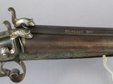 a close up of a gun on a table with a glass
