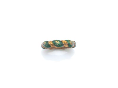 un gros plan d'une bague verte et dorée posée sur une surface blanche