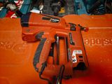 a corded nail gun sitting on top of an orange box