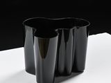 three black vases sitting on a table with a black background