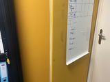 un tableau blanc accroché au mur, à côté d'une cloison jaune