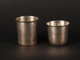 two silver cups sitting side by side on a black surface