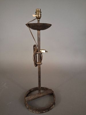 une lampe à l'ancienne posée sur un pied en métal, posée sur une surface blanche