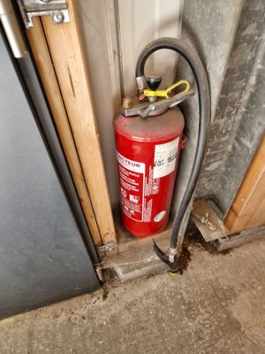 a fire extinguisher next to a door with a hose attached to it