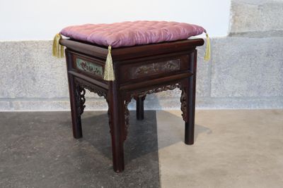 un petit tabouret en bois sur lequel est posé un coussin rose