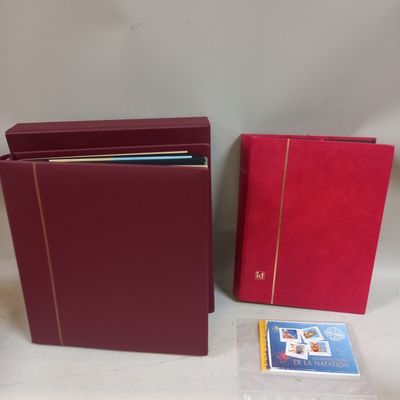 Deux classeurs rouges et un livre sont posés sur une table
