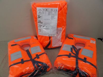 trois gilets de sauvetage orange posés les uns à côté des autres sur une table