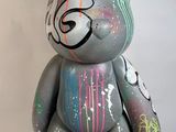 un ours en peluche gris qui a été peint avec de la peinture colorée