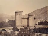 an old photo of a castle with a bridge in the foreground