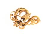 une image représentant une broche en forme de dragon en or, avec un diamant dans la gueule