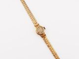 a gold wrist watch on a white surface