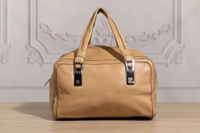 a tan handbag sitting on top of a wooden table next to a wall
