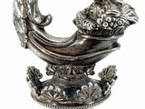 a silver vase with a bird on top of it