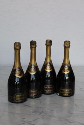 four bottles of champagne are lined up on a marble table