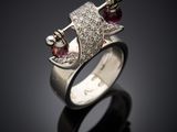 a close up of a silver ring with a red stone