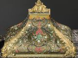 an ornate gold and green box with flowers on it on a marble surface