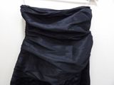 navy blue dress hanging on a hanger on a white wall