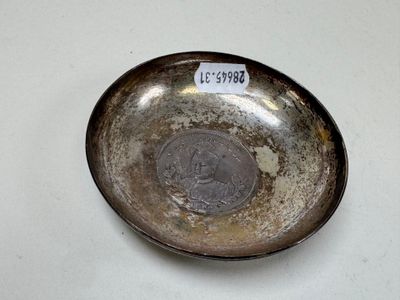 a silver plate with a coin on it sitting on a table