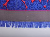 blue and red patterned scarf with fringes on a white surface