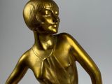 bronze statue of a woman sitting on a rock with her hands on her hips