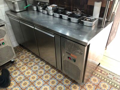 un plan de travail en acier inoxydable sur lequel sont posés des casseroles et des poêles, dans une cuisine