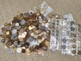 beaucoup de pièces de monnaie dans un récipient en plastique posé par terre