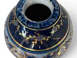 a blue and gold vase on a white surface