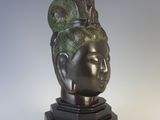 bronze head of a woman with a green hair on a black base