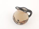 a small vase with a black handle sitting on a white surface