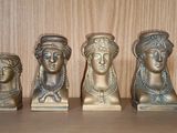 quatre petits bustes en bronze représentant des femmes, posés sur une étagère dans une pièce