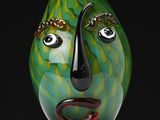 a green vase with a face on it on a table