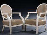 pair of white chairs with beige upholstered cushions against a black background