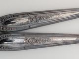 two silver spoons with gold handles on a white surface
