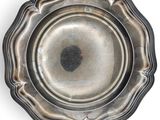 une assiette en argent ancien sur fond blanc, ornée d'un point noir