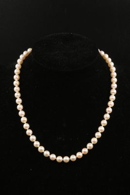 a white pearl necklace on a black mannequin