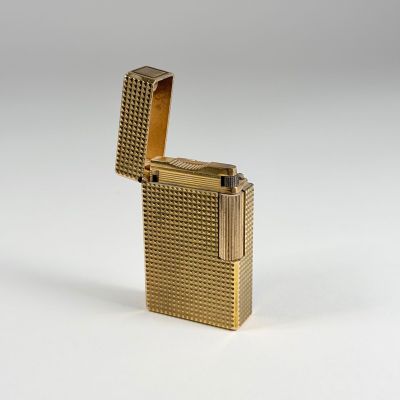 un briquet plaqué or posé sur une surface blanche