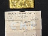 a gold bar sitting on top of a piece of paper next to a piece of paper