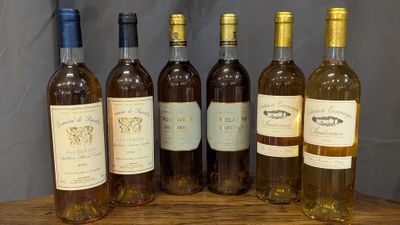 six bottles of wine are lined up on a wooden table