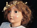 a close up of a doll with a flower crown on her head