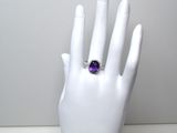 une main sur laquelle est passée une bague sertie d'une pierre violette