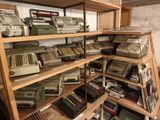 a lot of old typewriters on the shelves in the room