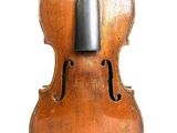 un vieux violon posé sur un pupitre, sur une surface blanche