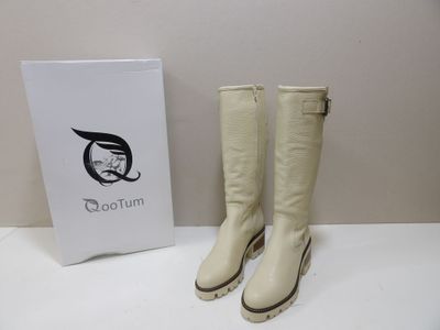 white leather boots with zippers and a box on a white table