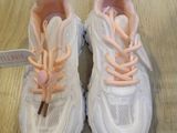 pair of white sneakers with pink laces on them sitting on a wooden floor