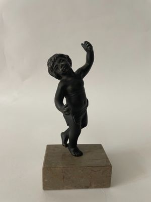 statue of a little boy on a wooden block holding a tennis racket