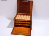 une petite boîte en bois contenant un cigare, posée sur une surface blanche