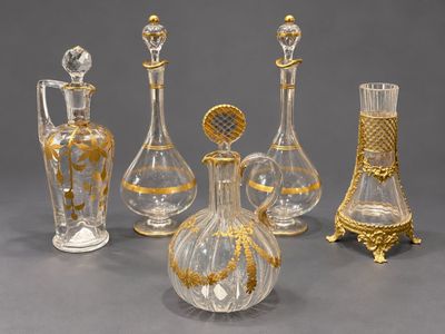 cinq vases en verre ornés de motifs dorés, posés sur une table