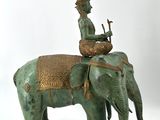 statue of a man riding an elephant with a basket on its back