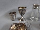 silver objects on a table with a silver spoon and a silver cup